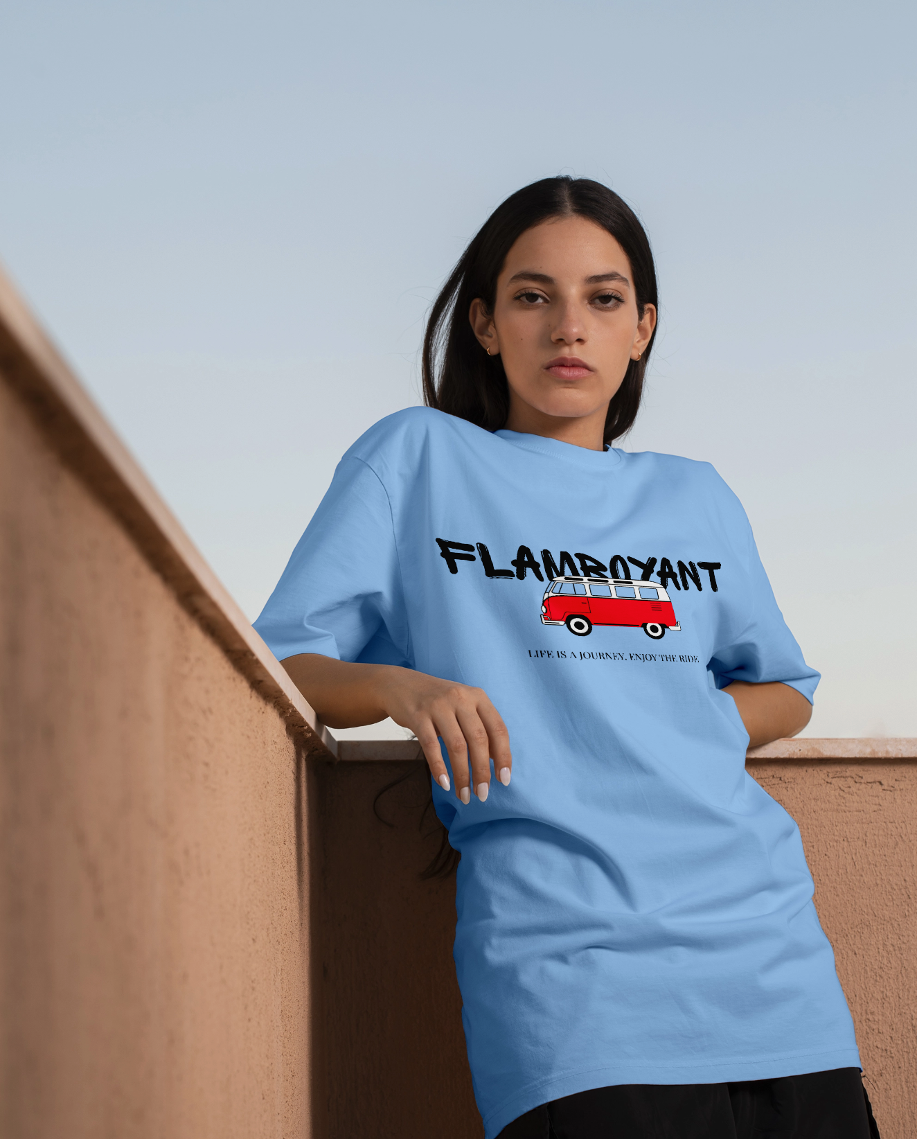 Person wearing a light blue t-shirt with a graphic design and text, sitting on a wooden bench.